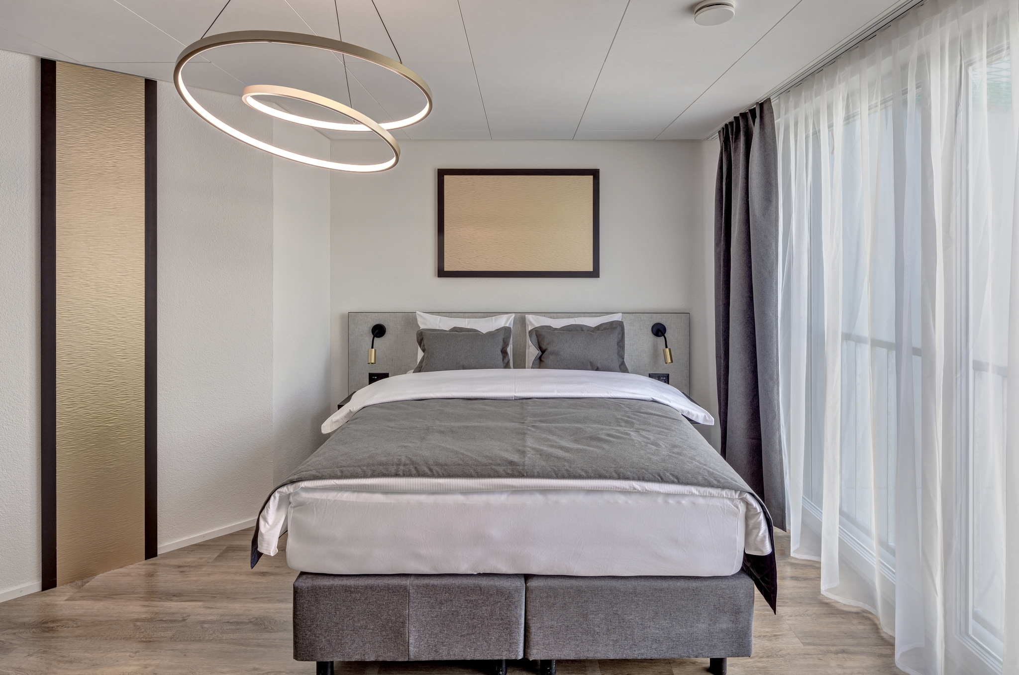 Blick auf ein großes Bett in Grautönen in den Serviced Apartments in der Schweiz
